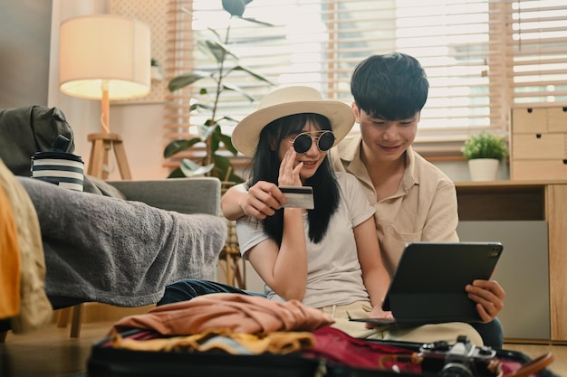 Una coppia allegra con una carta di credito e una prenotazione d'albergo su un tablet digitale