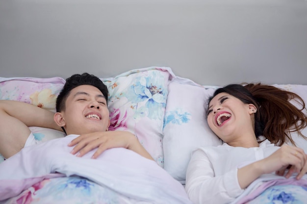 Una coppia asiatica che ride insieme in camera da letto.