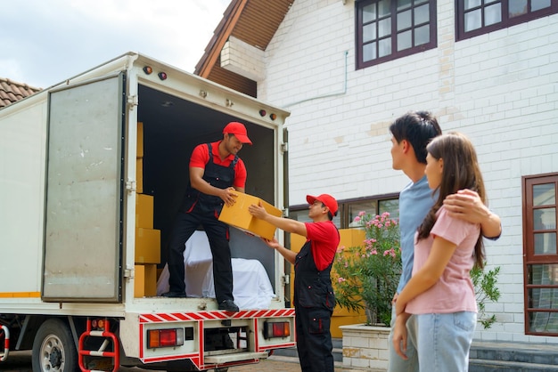 Una coppia asiatica guarda gli operai che si trasferiscono nella loro nuova casa