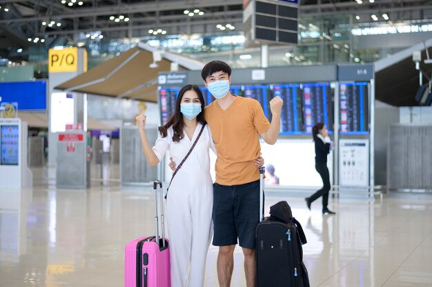 Una coppia asiatica indossa una maschera protettiva all'aeroporto internazionale, viaggia sotto la pandemia Covid-19,