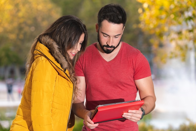 Una coppia carina che guarda un film su un tablet in un parco