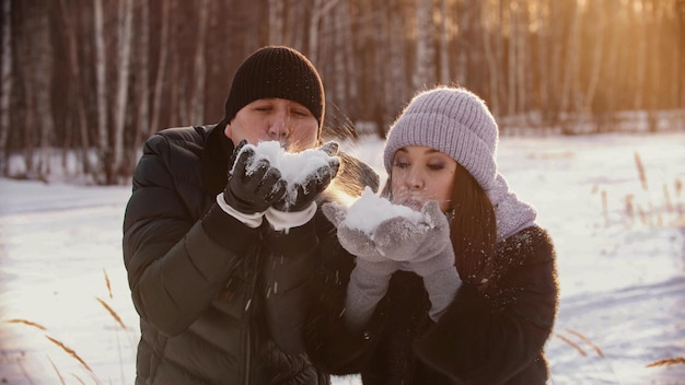 Una coppia carina sposata che soffia la neve dalle loro mani