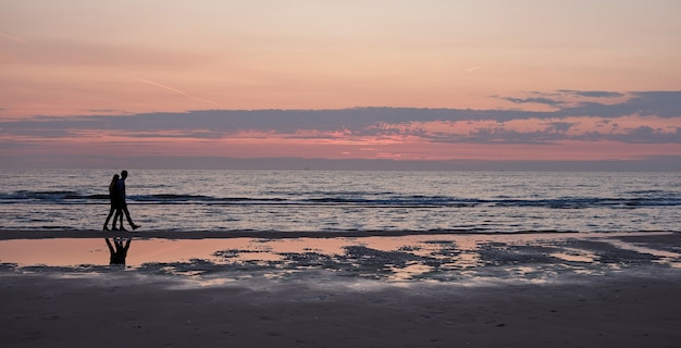 Una coppia che cammina e si gode un bel tramonto in spiaggia