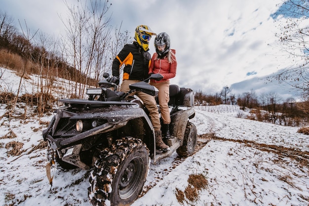 Una coppia che si diverte a guidare una quad sulla cima di una montagna in inverno