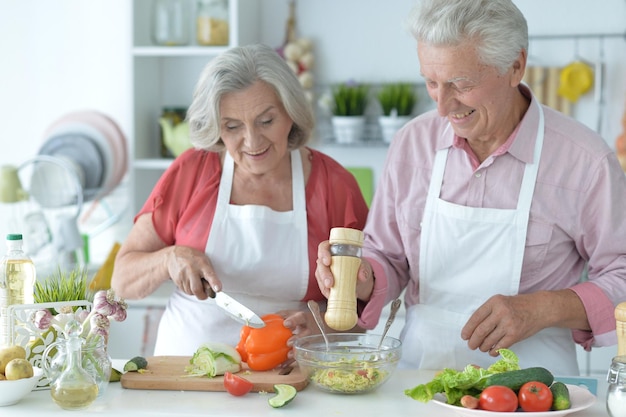 Una coppia di anziani che fanno insieme l'insalata in cucina