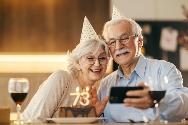 Una coppia di anziani sta facendo una videochiamata al telefono per un compleanno a casa