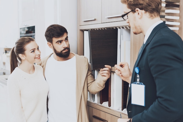 Una coppia di clienti con il manager sta scegliendo i materiali del gabinetto nel negozio di cucina.