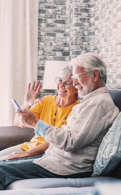 Una coppia di famiglie pensionate felici che usano il cellulare per le videoconferenze, che parlano insieme con i parenti, che ricevono buone notizie, che si divertono, che sorridono e ridono, che si preoccupano di pensionati maturi che chattano online sul cellulare.