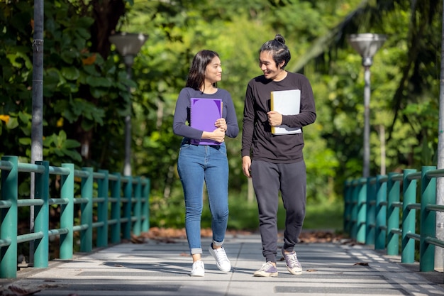 Una coppia di giovani studenti universitari diretti a lezione. Stanno facendo una passeggiata nel campus universitario mentre leggono un libro. L'autunno è una bella stagione.