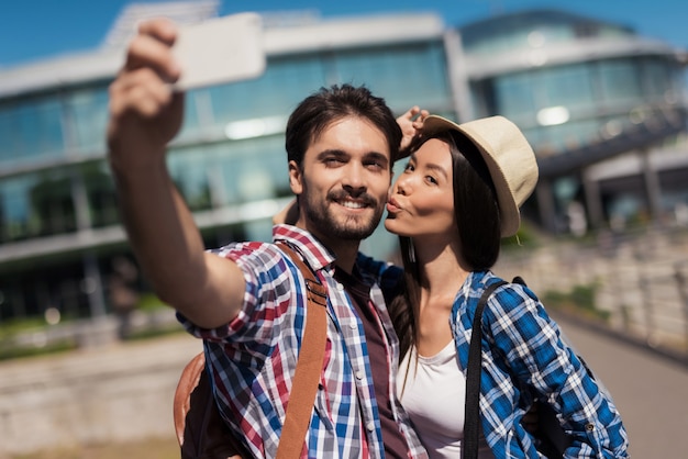 Una coppia di giovani turisti fa selfie.