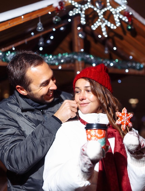 Una coppia di innamorati in città a piedi beve un caffè con caramelle di Natale in inverno.