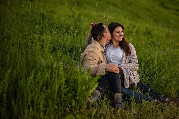 Una coppia di innamorati si trova e fa l'amore tra il prato al tramonto. Copia spazio Una coppia innamorata si trova su un prato verde e si bacia