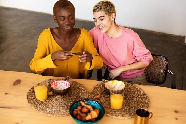 Una coppia di lesbiche che fotografano la colazione sul tavolo a casa