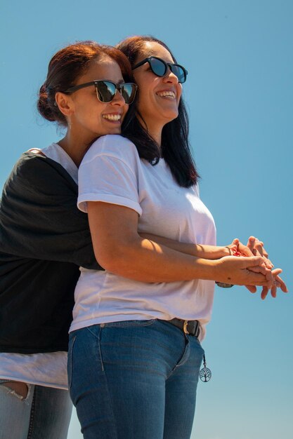 Una coppia di lesbiche che si abbracciano contro un cielo limpido.