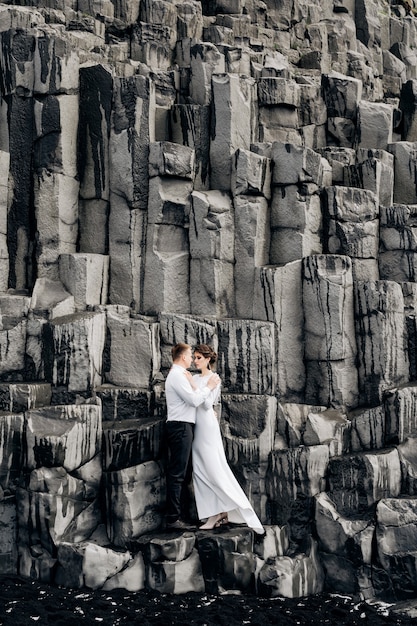 Una coppia di sposi si trova su un muro di pilastri di pietra che gli sposi stanno abbracciando su kekurs di basalto