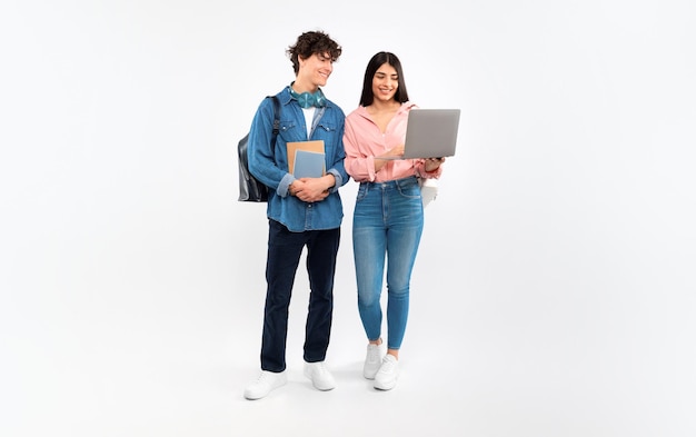 Una coppia di studenti felici che usano il portatile per studiare su uno sfondo bianco