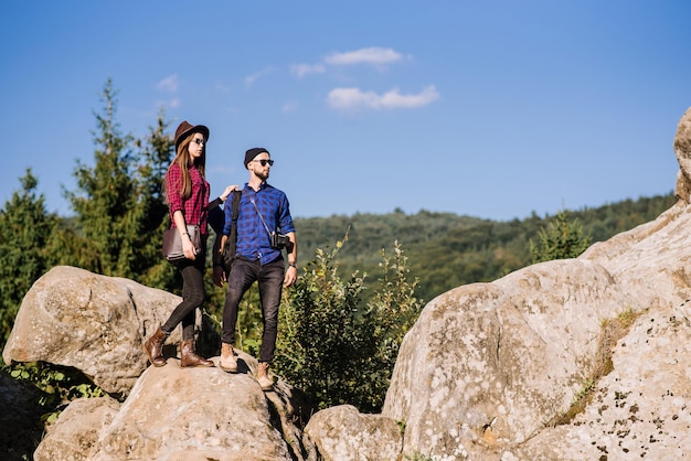 Una coppia di viaggiatori in piedi insieme sulle rocce in montagna sullo sfondo del cielo blu