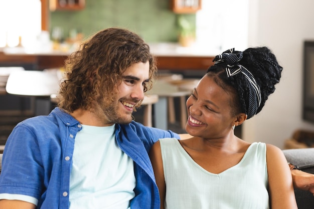 Una coppia diversa, una giovane donna afroamericana e un uomo caucasico, condividono un momento di gioia sul divano.