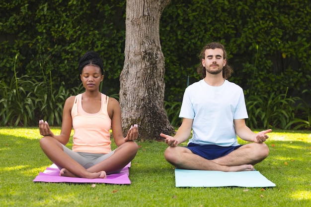 Una coppia diversa una giovane donna afroamericana e un uomo caucasico meditano in un giardino sereno