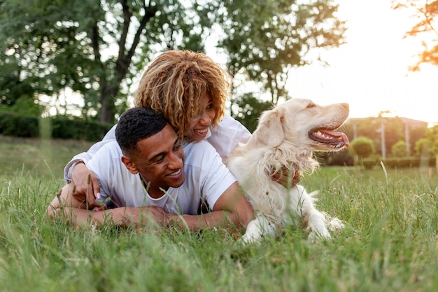 Una coppia felice afroamericana giace insieme al cane nel parco in estate.