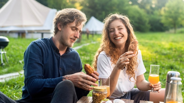 Una coppia felice che riposa nella natura al glamping. Bevande e cibo, verde intorno