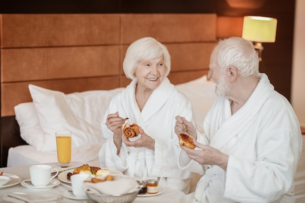 Una coppia felice senior che gode della colazione mentre sta a letto