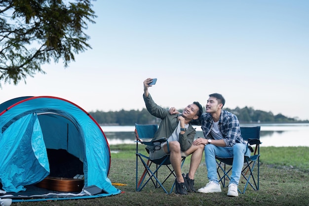 Una coppia gay asiatica felice che campeggia insieme in una foresta in un viaggio di vocazione romantica.