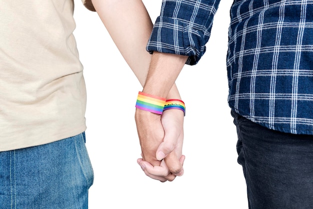 Una coppia gay con un braccialetto con bandiera arcobaleno LGBT che si tiene per mano insieme in piedi