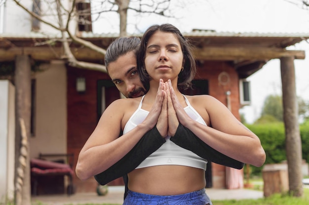 Una coppia in meditazione che tiene i palmi delle mani insieme all'aperto