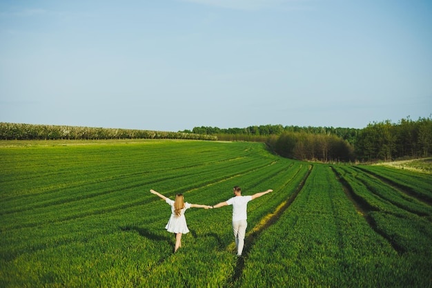 Una coppia incinta che si abbraccia in un verde campo primaverile genitori in attesa nel parco di alberi a fiori bianchi una coppia romantica che aspetta un bambino una passeggiata in un verde campo