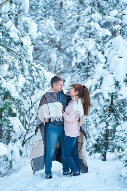 Una coppia innamorata che si bacia mentre cammina attraverso una foresta invernale favolosamente innevata