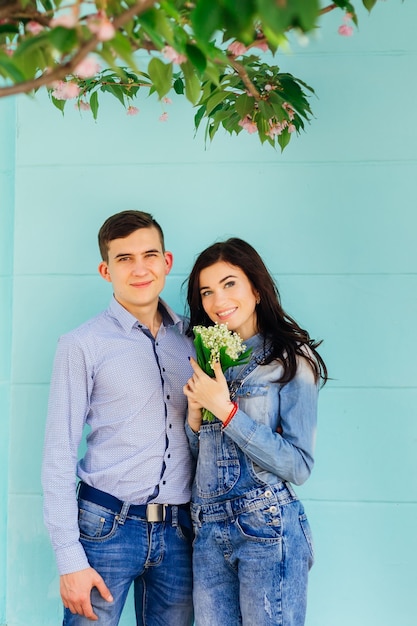 Una coppia innamorata in abiti in denim. La donna tiene un mazzo di fiori