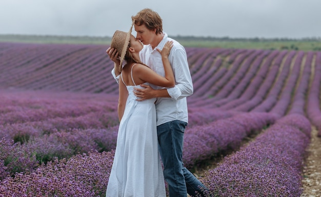 Una coppia innamorata in un campo di lavanda in abiti bianchi