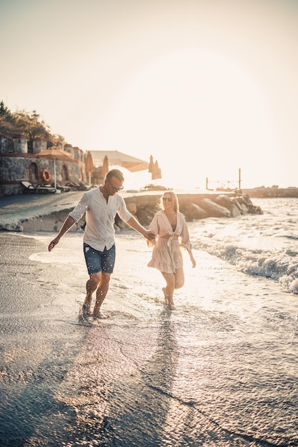 Una coppia innamorata sta camminando sulla spiaggia vicino al mare Famiglia giovane al tramonto sul Mar Mediterraneo Concetto di vacanza estiva