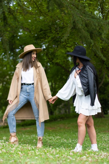 Una coppia lesbica alla moda che si tiene per mano e che cammina nel parco