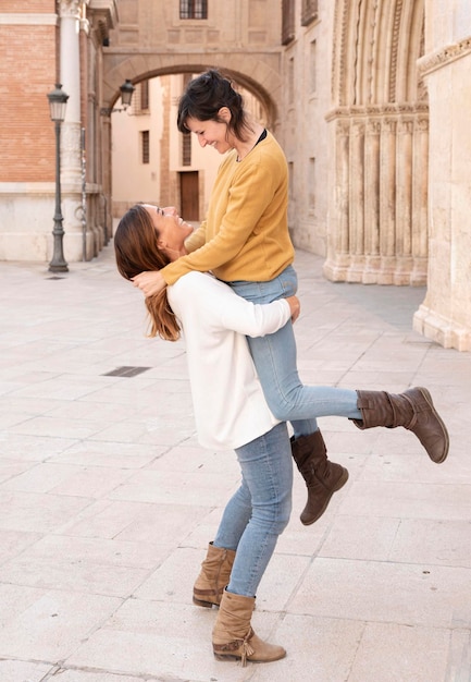 Una coppia lesbica si diverte per le strade di Valencia sollevandosi a vicenda su un concetto gay