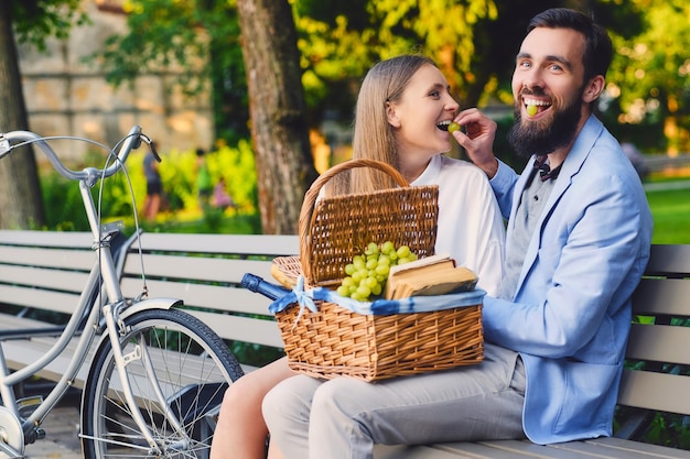 Una coppia mangia l'uva su una panchina in un parco.