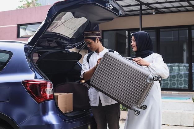 Una coppia musulmana sta spostando la valigia nel bagagliaio dell'auto. Mudik lebaran al momento dell'Eid.