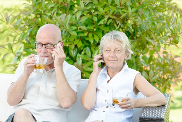 Una coppia seduta ciascuno con un telefono