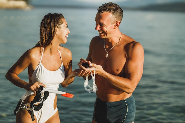 Una coppia sorridente che si diverte e tiene in mano un riccio di mare dopo lo snorkeling in mare.