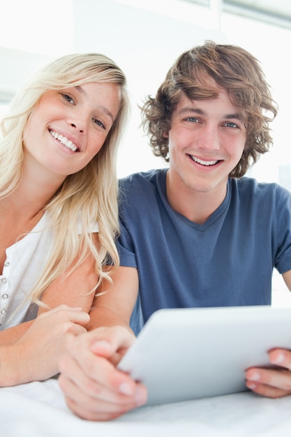 Una coppia sorridente in possesso di un tablet e guardando la telecamera