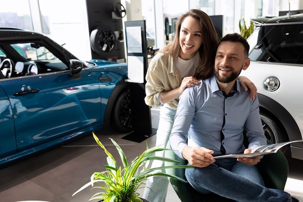 Una coppia sposata che studia i termini della nuova assicurazione auto presso un concetto di sicurezza stradale di un concessionario di automobili