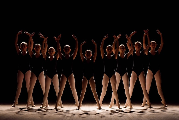 Una coreografia di un gruppo di graziose e graziose ballerine che si esercitano sul palco di una scuola di danza classica.