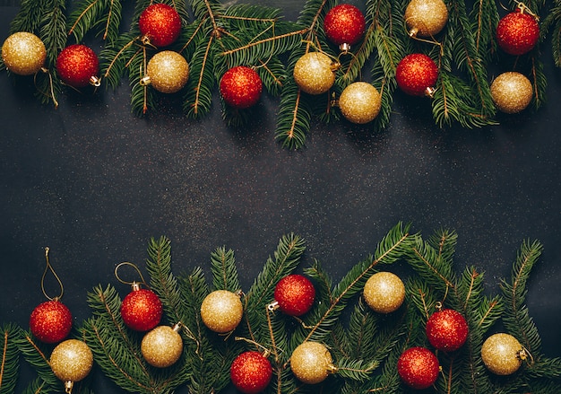 Una cornice di abete verde e giocattoli di Natale su uno sfondo nero con spazio vuoto