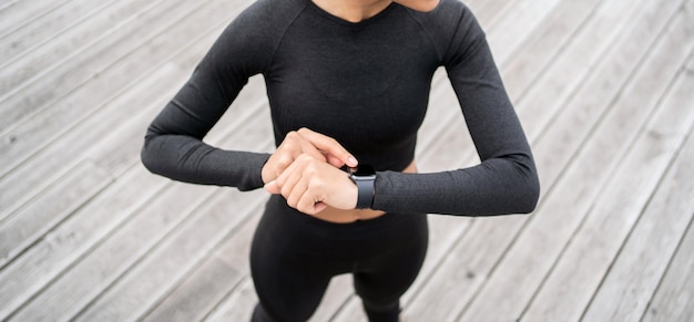Una corridore femminile utilizza un orologio fitness per l'allenamento l'allenatore è vestito con una tuta da ginnastica