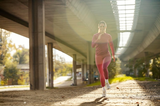 Una corridore sta facendo jogging in esterno urbano durante il suo allenamento cardio