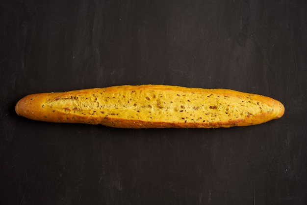 Una croccante baguette francese giacciono sfondo nero tavolo scuro