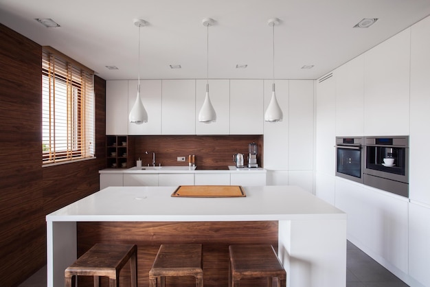 Una cucina con un bancone bianco e un mobile in legno con tre lampade a sospensione