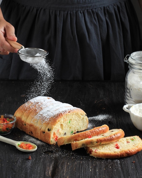 Una cuoca cosparge la farina su un impasto arrotolato per stollen attraverso un colino piccolo. Movimento congelato