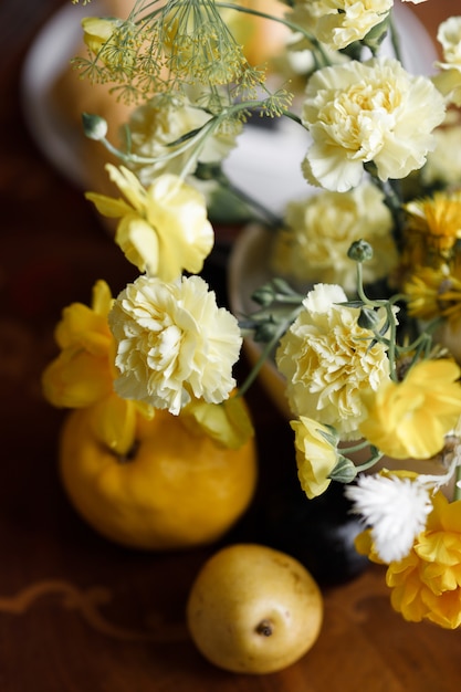 Una delicata composizione con fiori e frutti gialli con partecipazioni di nozze Decorazioni per matrimoni